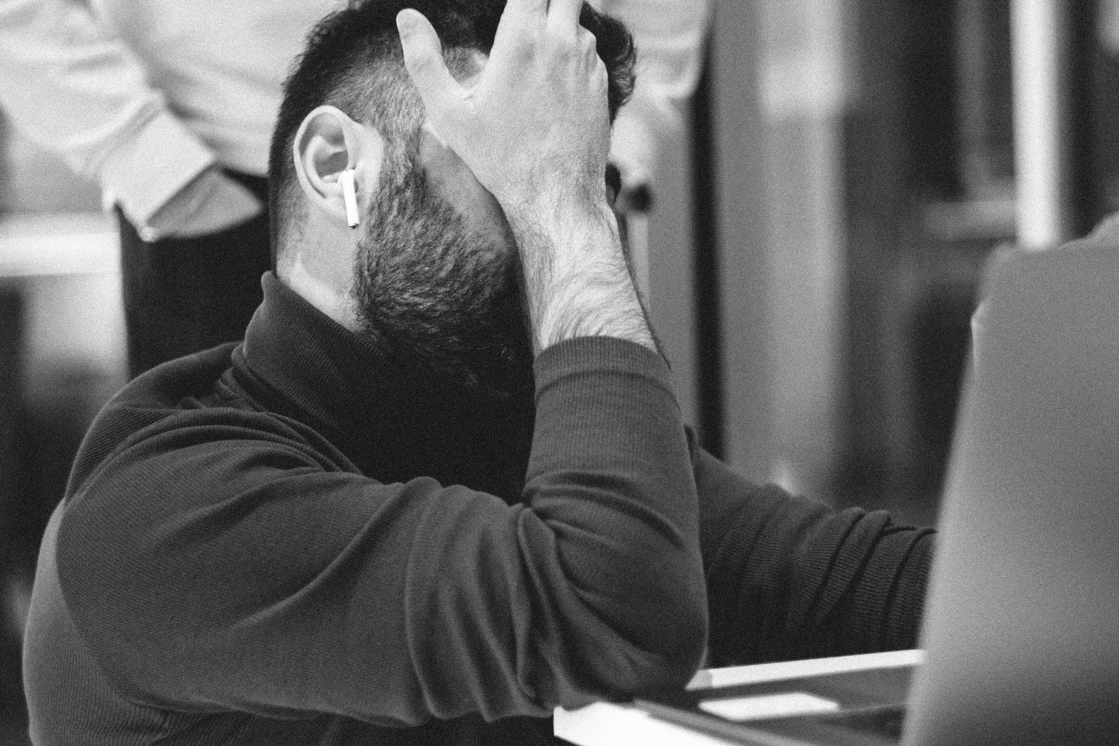 Stressed executive with head in hands at a laptop
